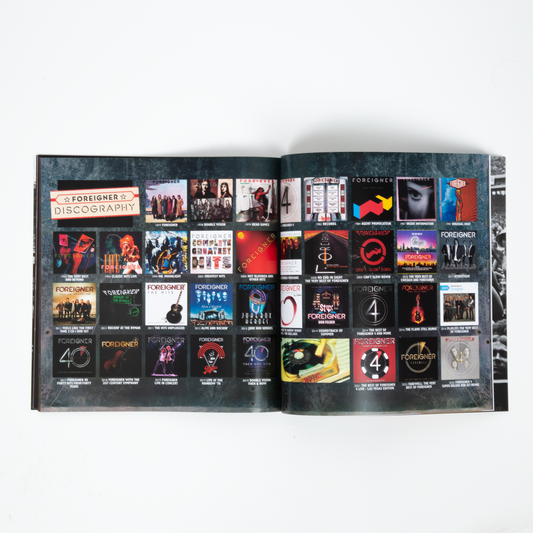 An open tour book displaying a printed discography spread with multiple album covers and text reading 'Foreigner Discography'