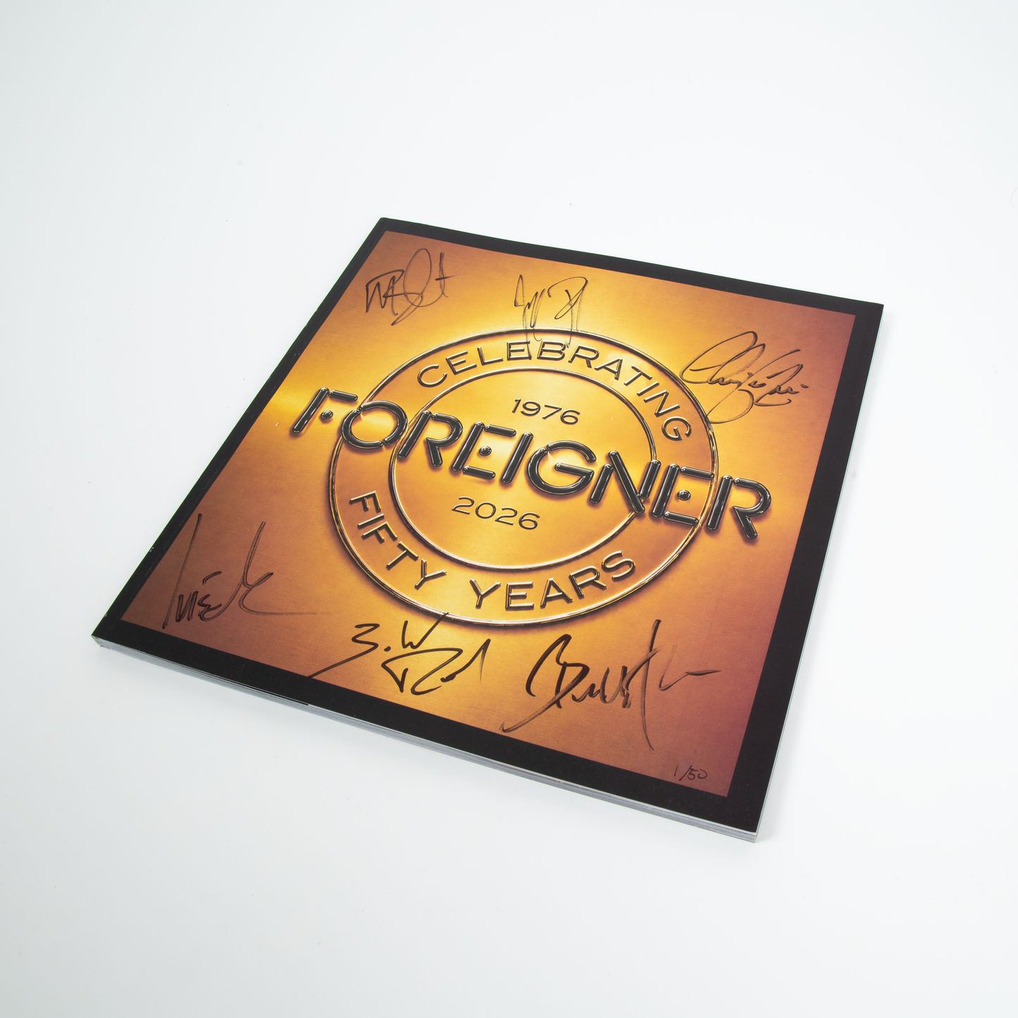 The front cover of the Foreigner Tour Book featuring a gold-to-orange gradient design with the text 'Celebrating Foreigner 1976 2026 Fifty Years' and multiple black autograph signatures by the members around the border, 