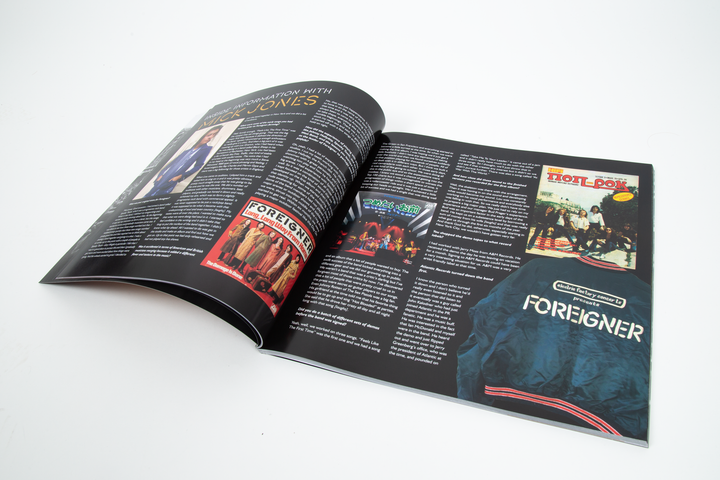 An open tour book spread with pages that are mostly black with several printed photos, text blocks, and colorful album-cover style graphics, including the word FOREIGNER prominently visible on the right page.